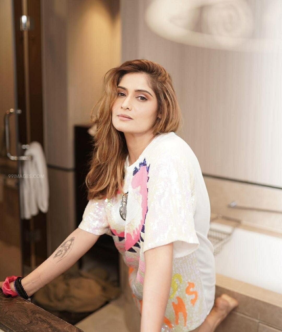 Arti Singh seated casually in a white printed t shirt image