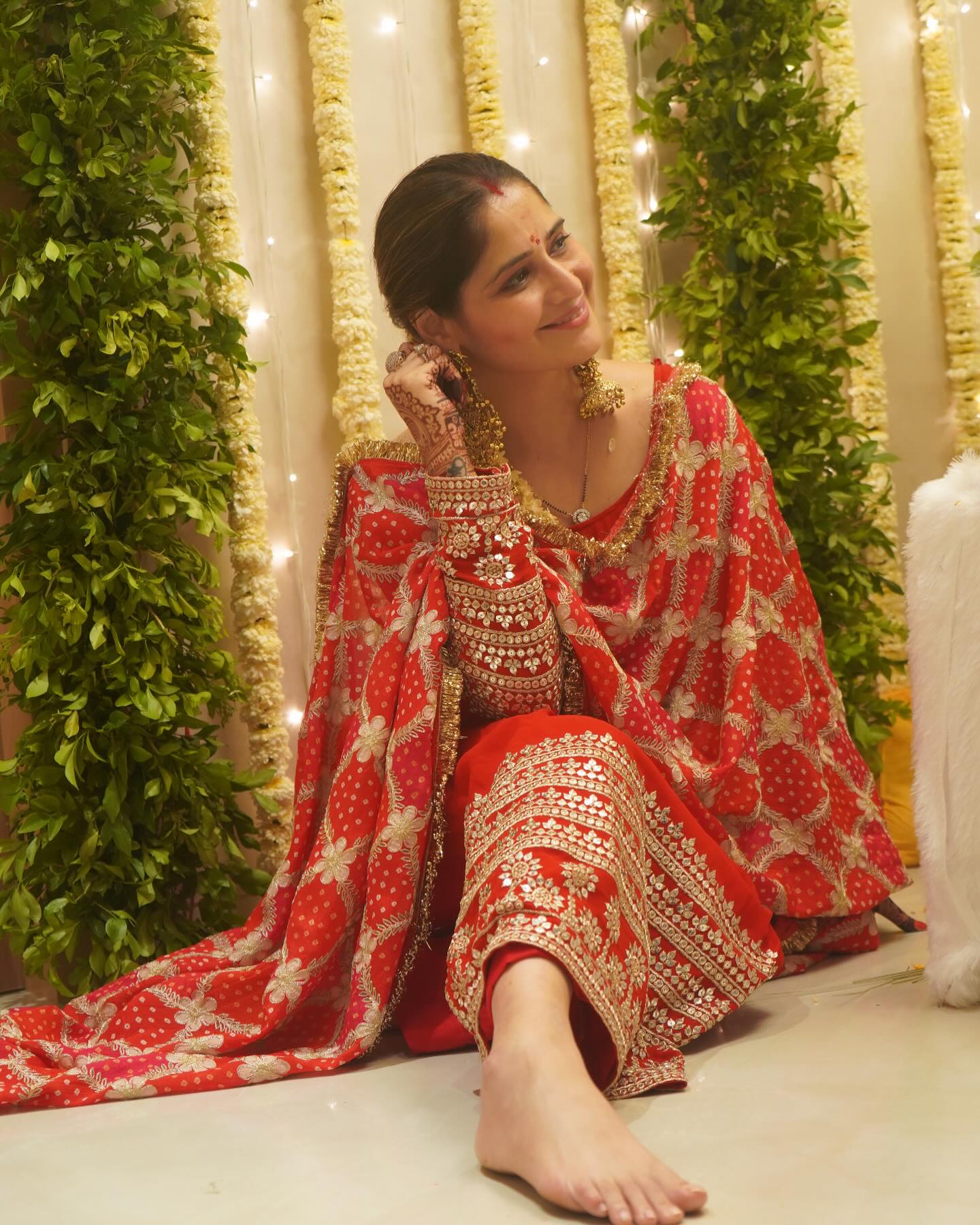 Arti Singh sitting peacefully in a vibrant red ethnic suit