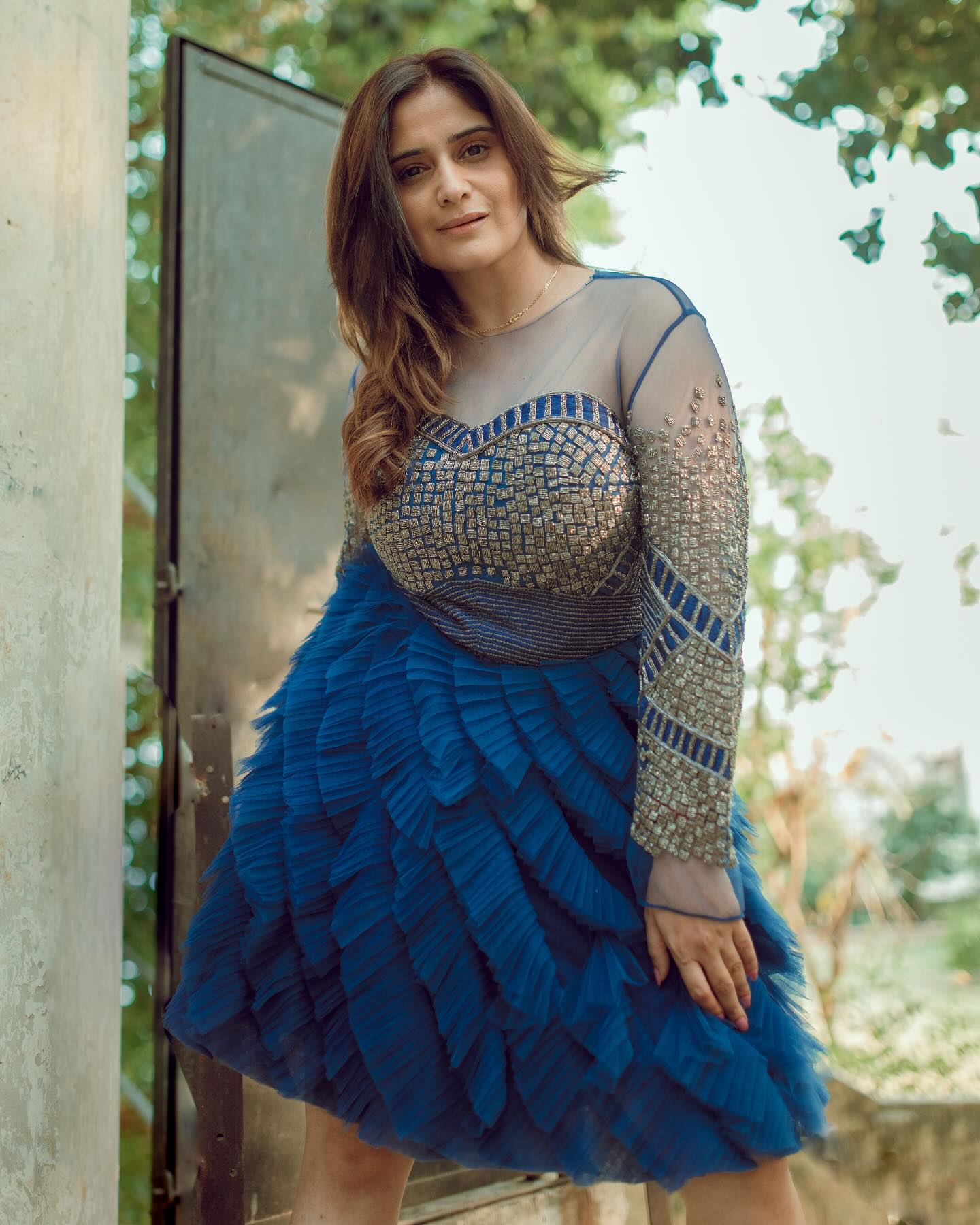 Arti Singh posing elegantly in a layered blue gown dress