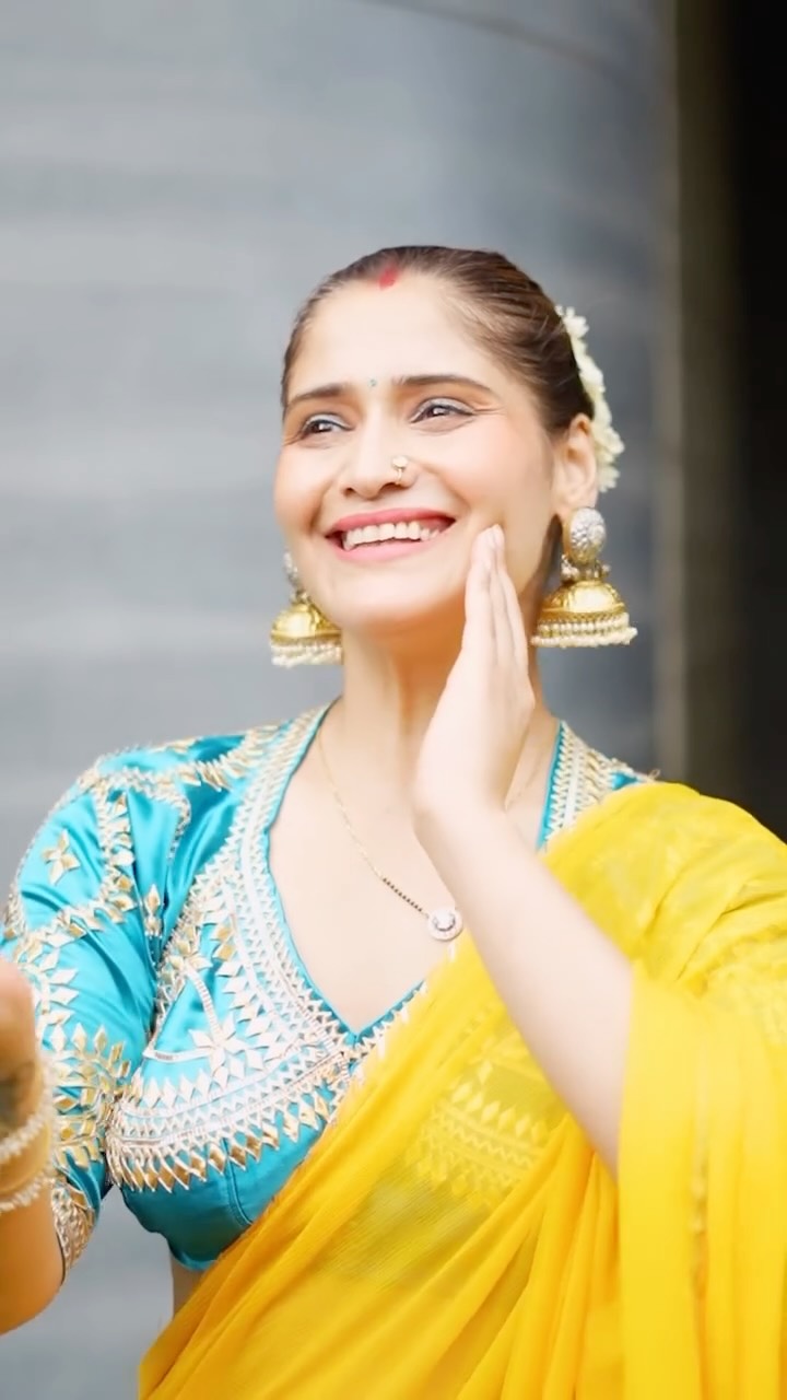 Arti Singh in blue and yellow saree flashing a bright smile