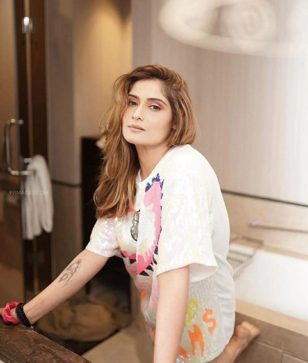 Arti Singh seated casually in a white printed t shirt image