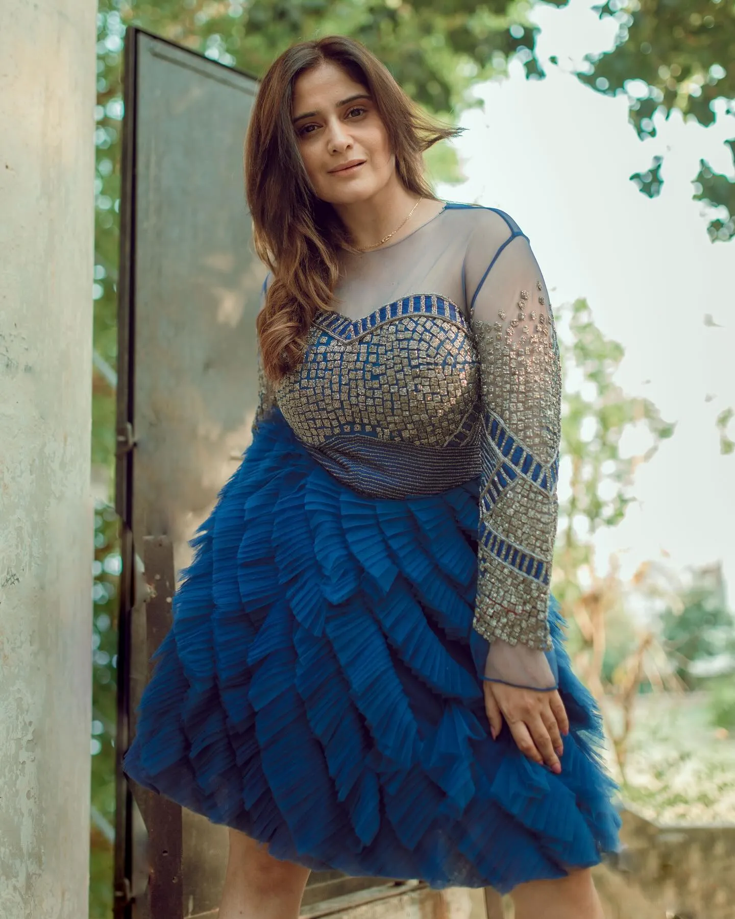 Arti Singh posing elegantly in a layered blue gown dress