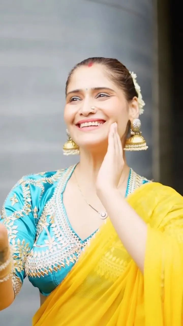 Arti Singh in blue and yellow saree flashing a bright smile