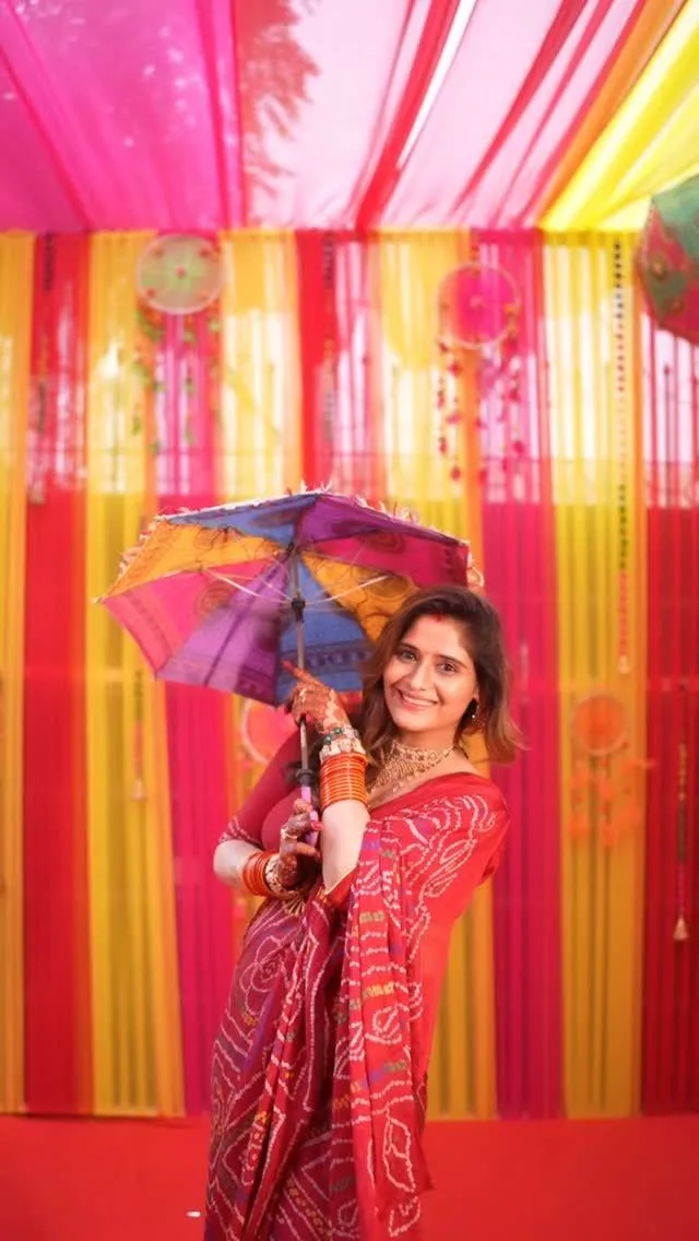 Arti Singh holds a colorful umbrella at festive event setup