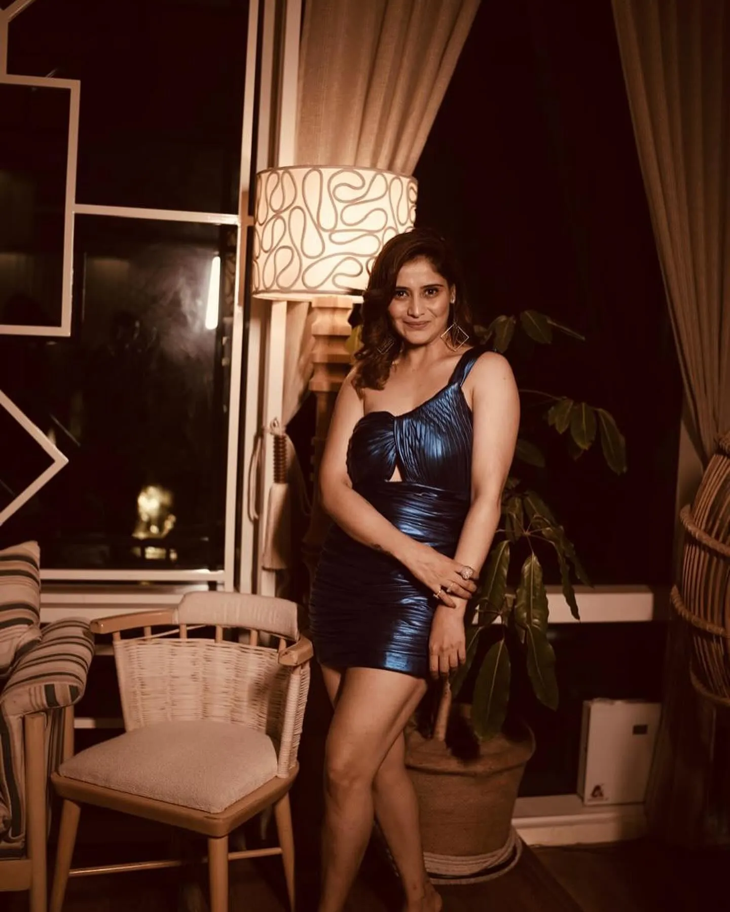 Arti Singh in a blue dress poses in an elegant room setting