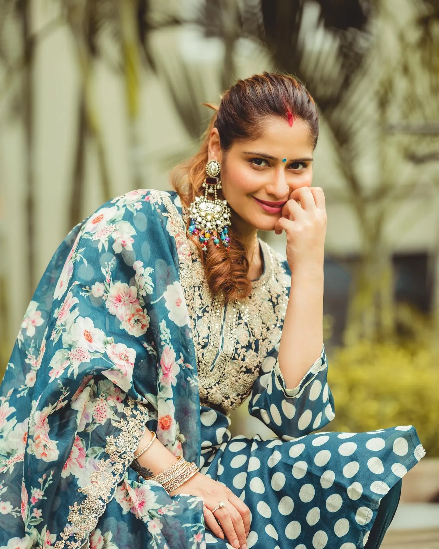 Arti Singh in a floral blue dress smiling in an outdoor park