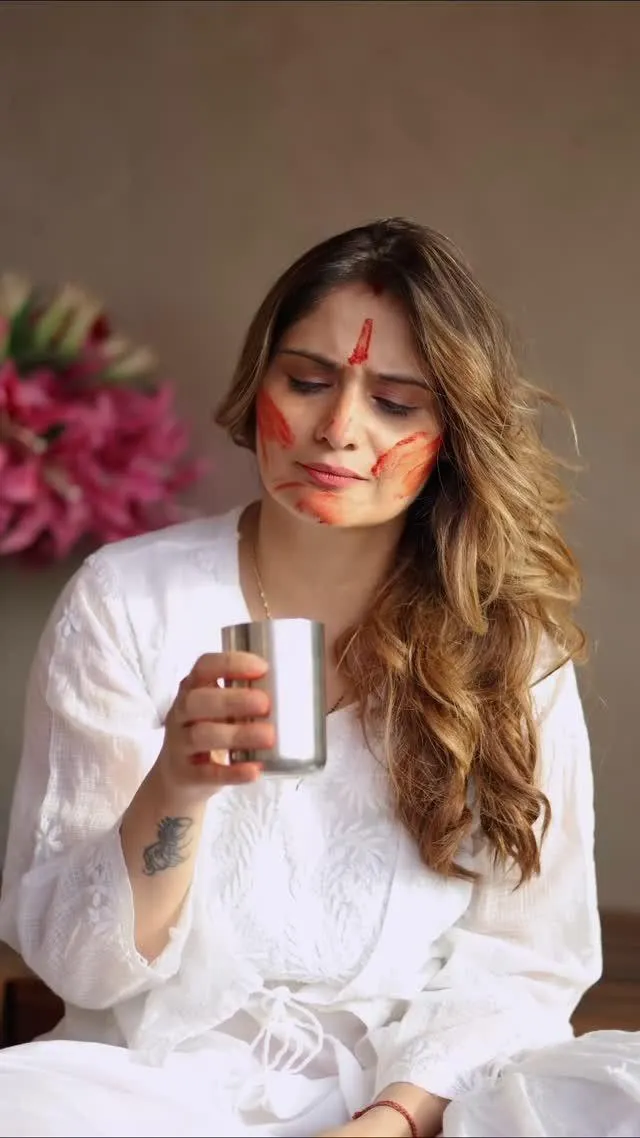 Arti Singh in white outfit holding a cup and smiling softly