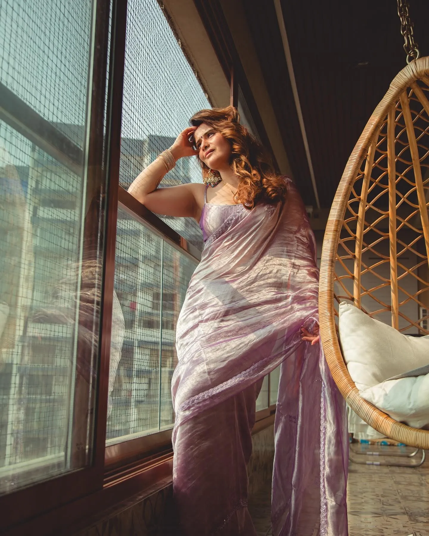 Arti Singh poses by window in a soft lilac saree and curls