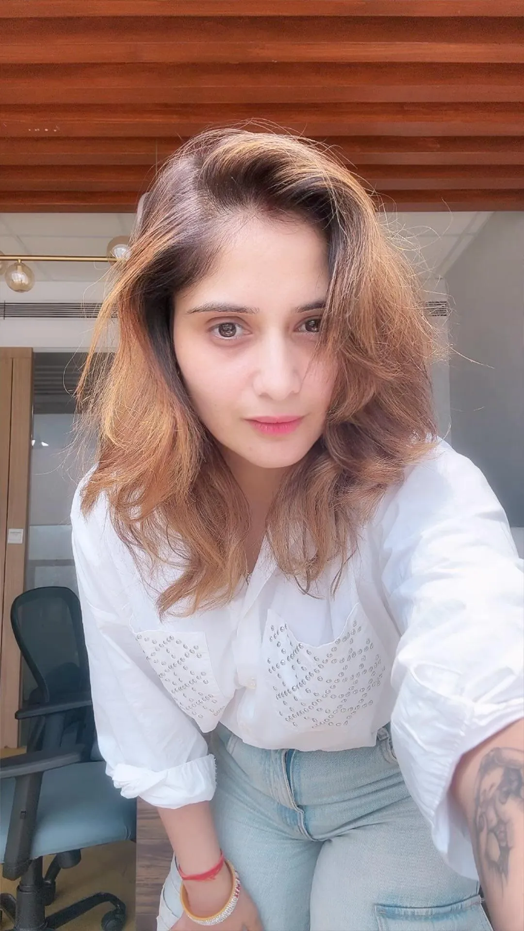 Arti Singh poses casually in a white top with soft curls