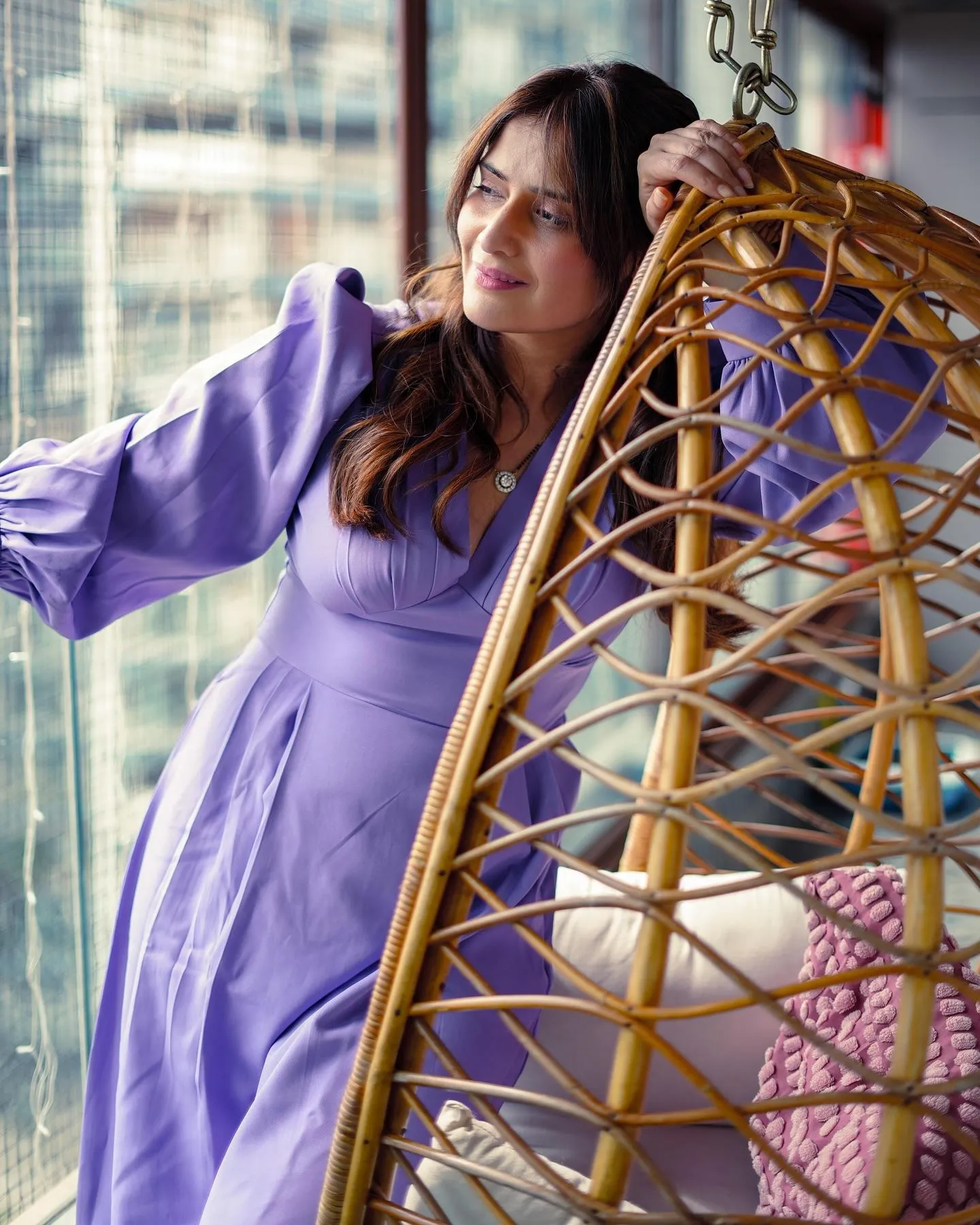 Arti Singh relaxes on a swing chair in a lavender dress