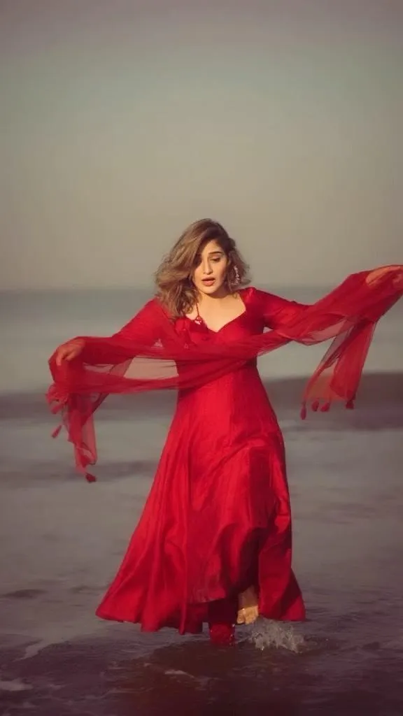 Arti Singh twirls joyfully in a flowing red dress on the beach