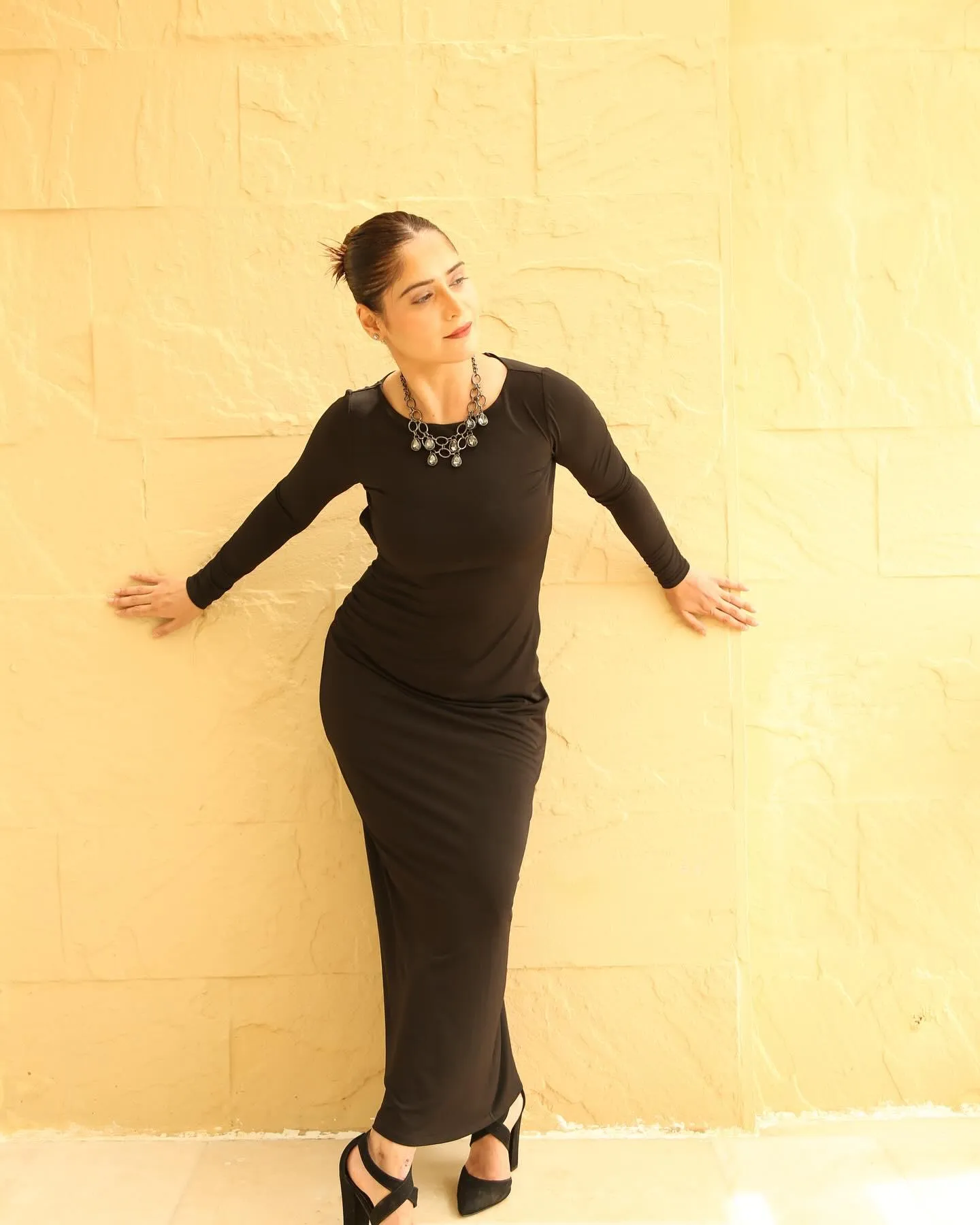 Arti Singh wears a fitted black gown with a playful pose