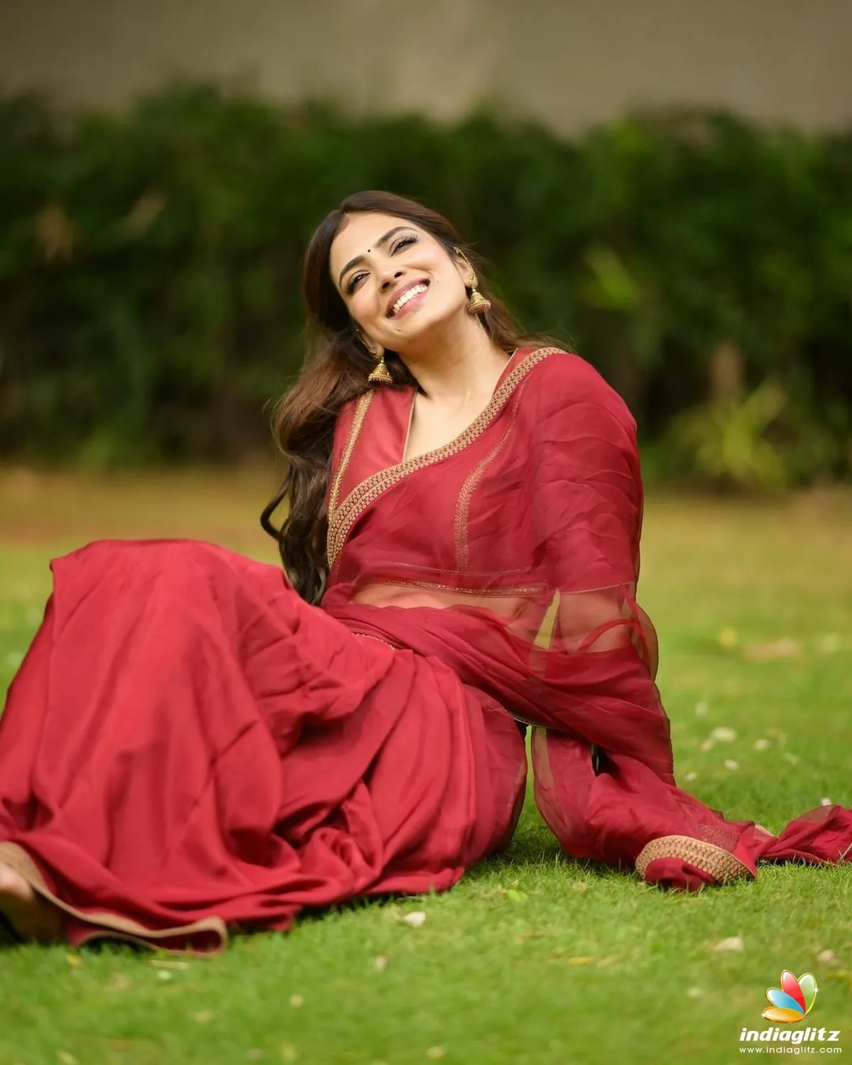 Charming Malavika Mohanan Sitting in Green Field Pose Image