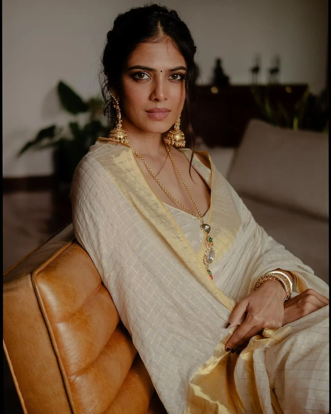 Hot Malavika Mohanan in Stylish White Saree on Armchair Pose