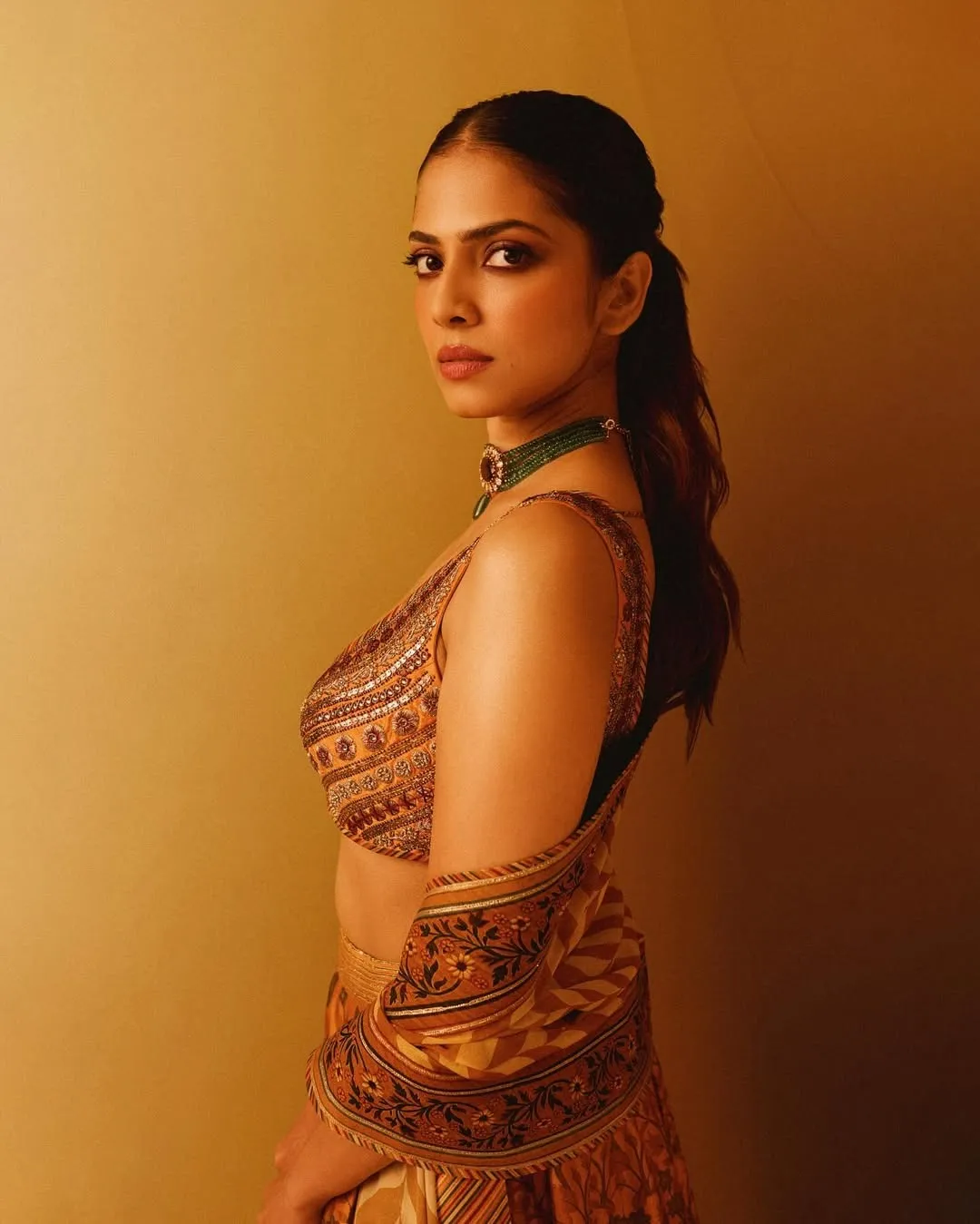 Sultry Malavika Mohanan in Orange Dress Backlit Image