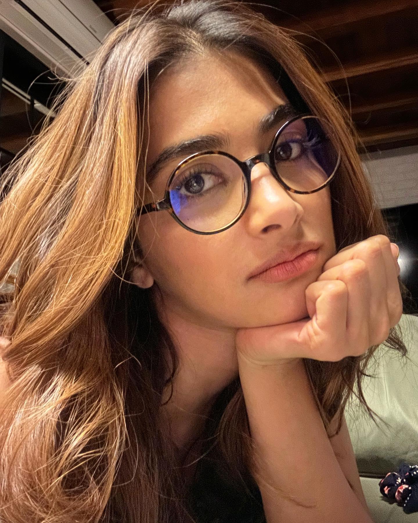 Pooja Hegde in Glasses Resting Her Face on Hand Indoors