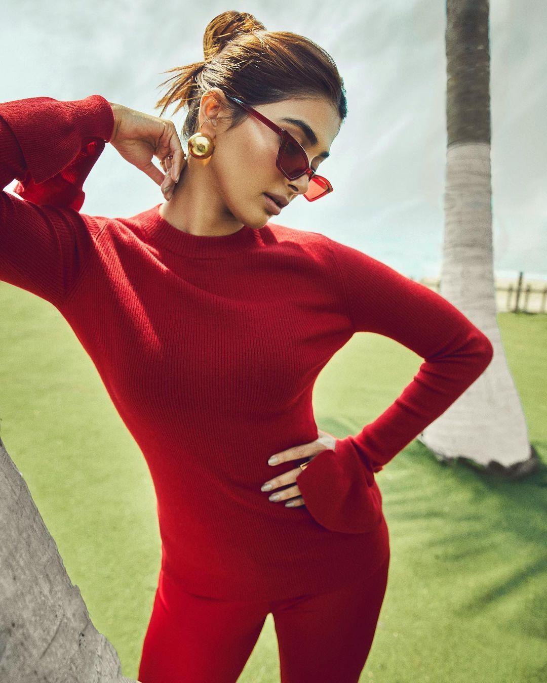 Pooja Hegde in Red Dress Posing Beside a Palm Tree Image