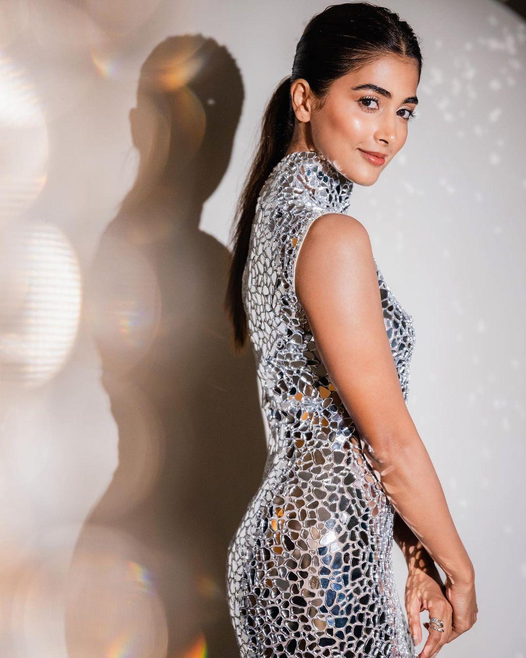 Pooja Hegde in Silver Dress Leaning on Glass Wall