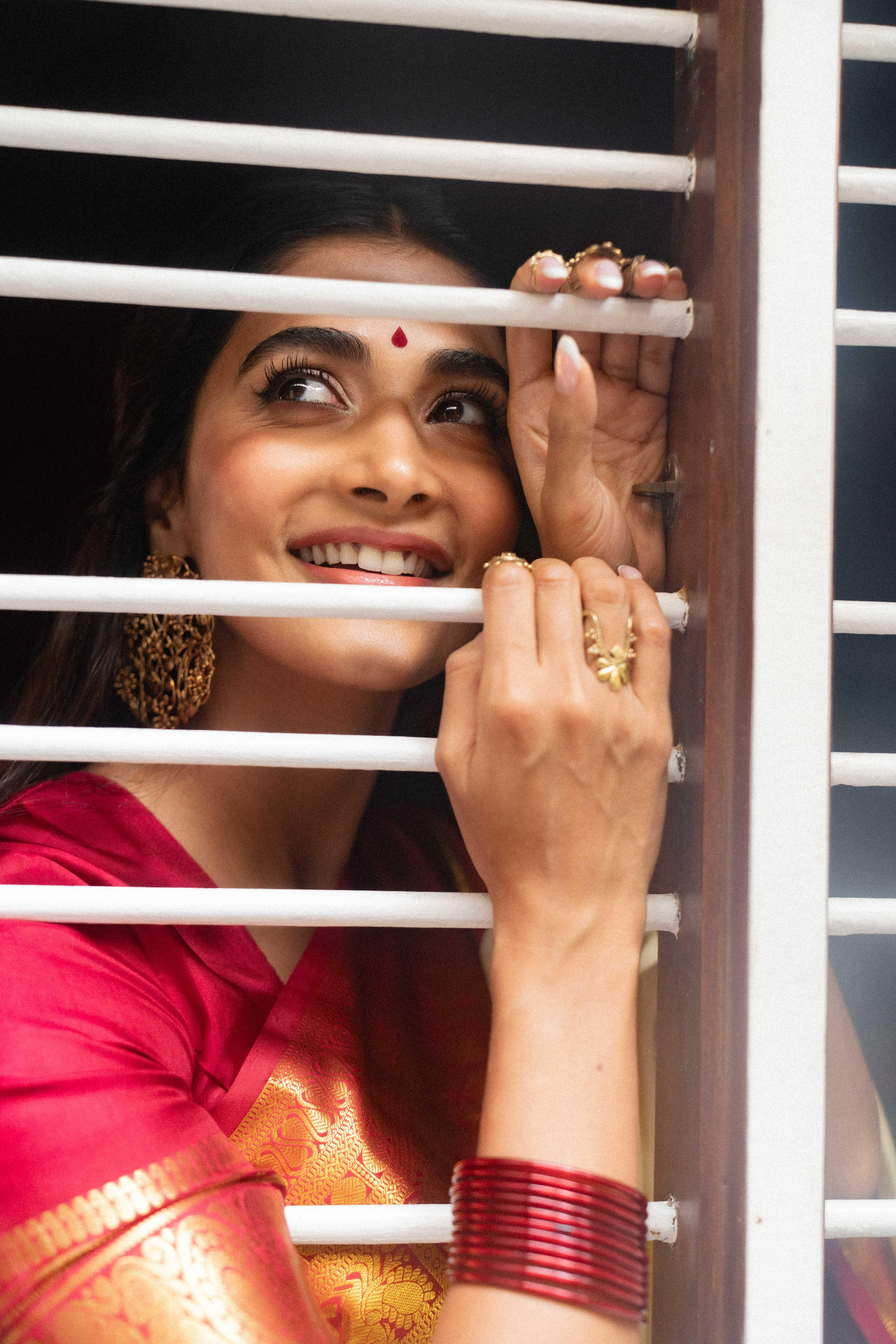 Pooja Hegde in Traditional Attire Smiling Behind Window Grill