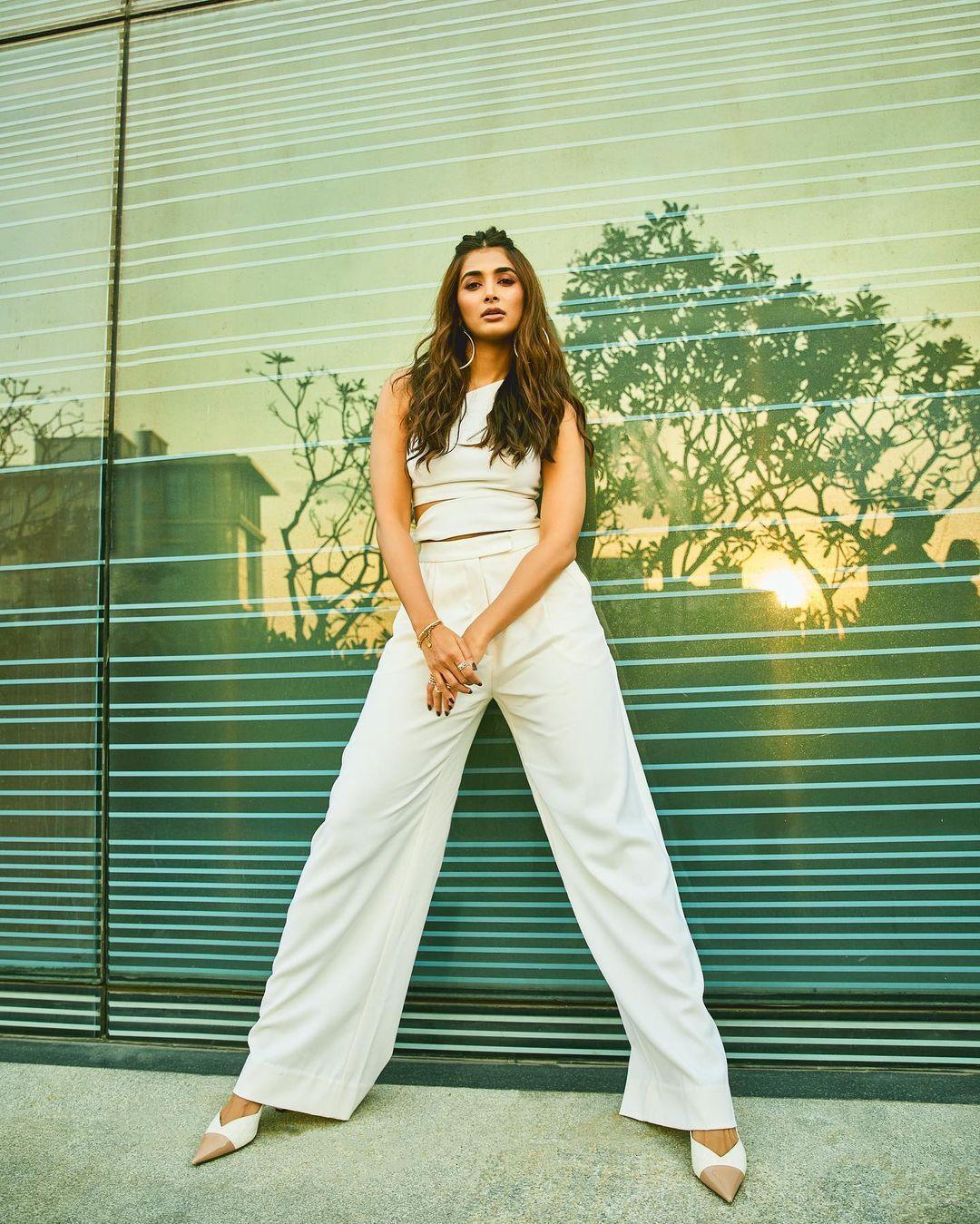 Pooja Hegde in White Pantsuit Standing Near Glass Wall