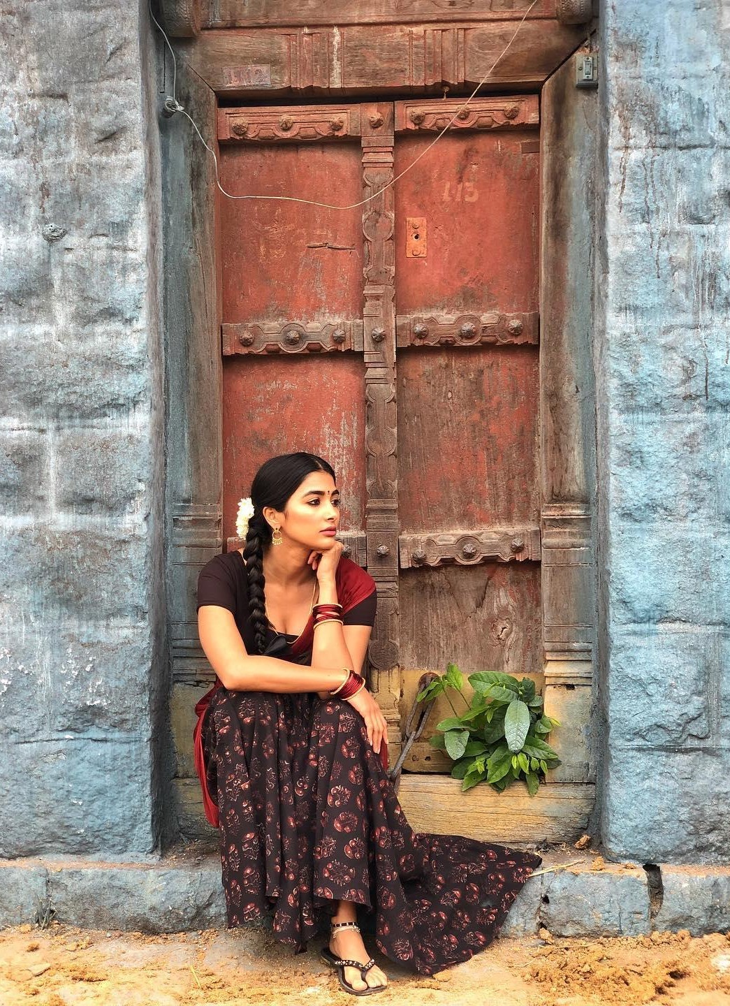 Pooja Hegde Sits Near Old Red Door with Thoughtful Look