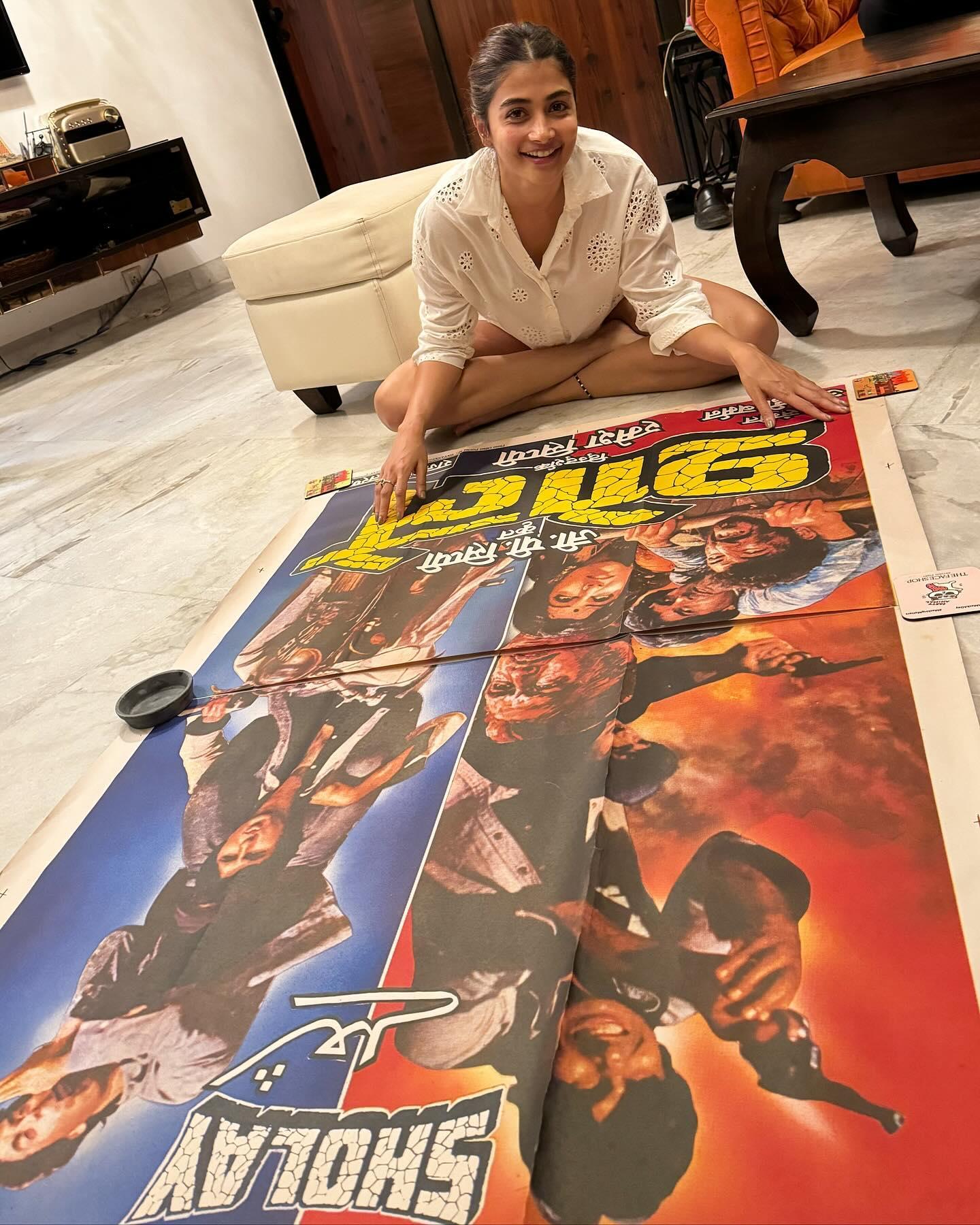 Pooja Hegde Sitting Beside Large Poster on the Floor