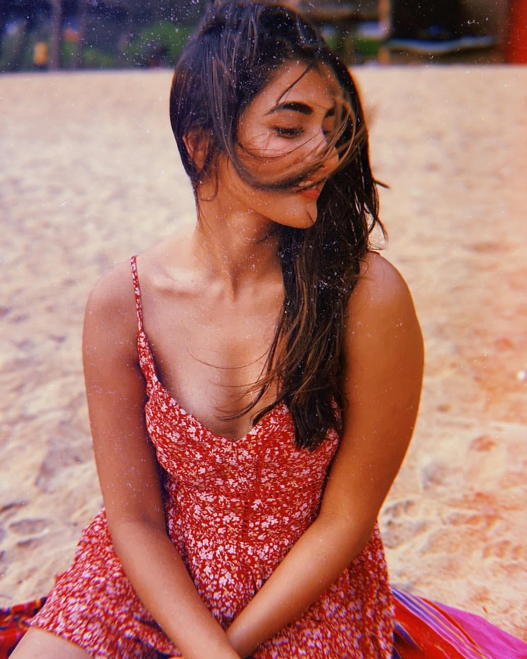 Pooja Hegde Sitting on Beach in Red Sleeveless Dress