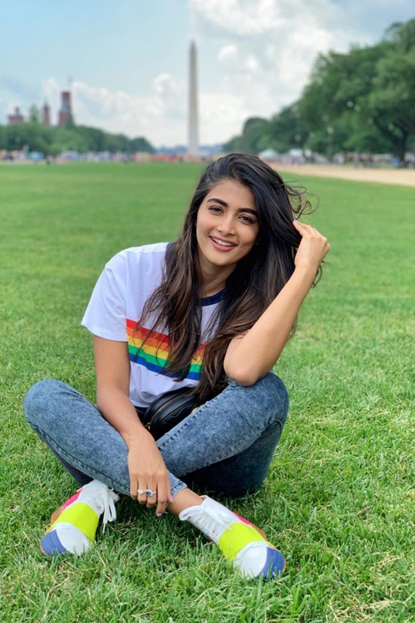 Pooja Hegde Smiling Sitting on Grass Wearing Casual Outfit