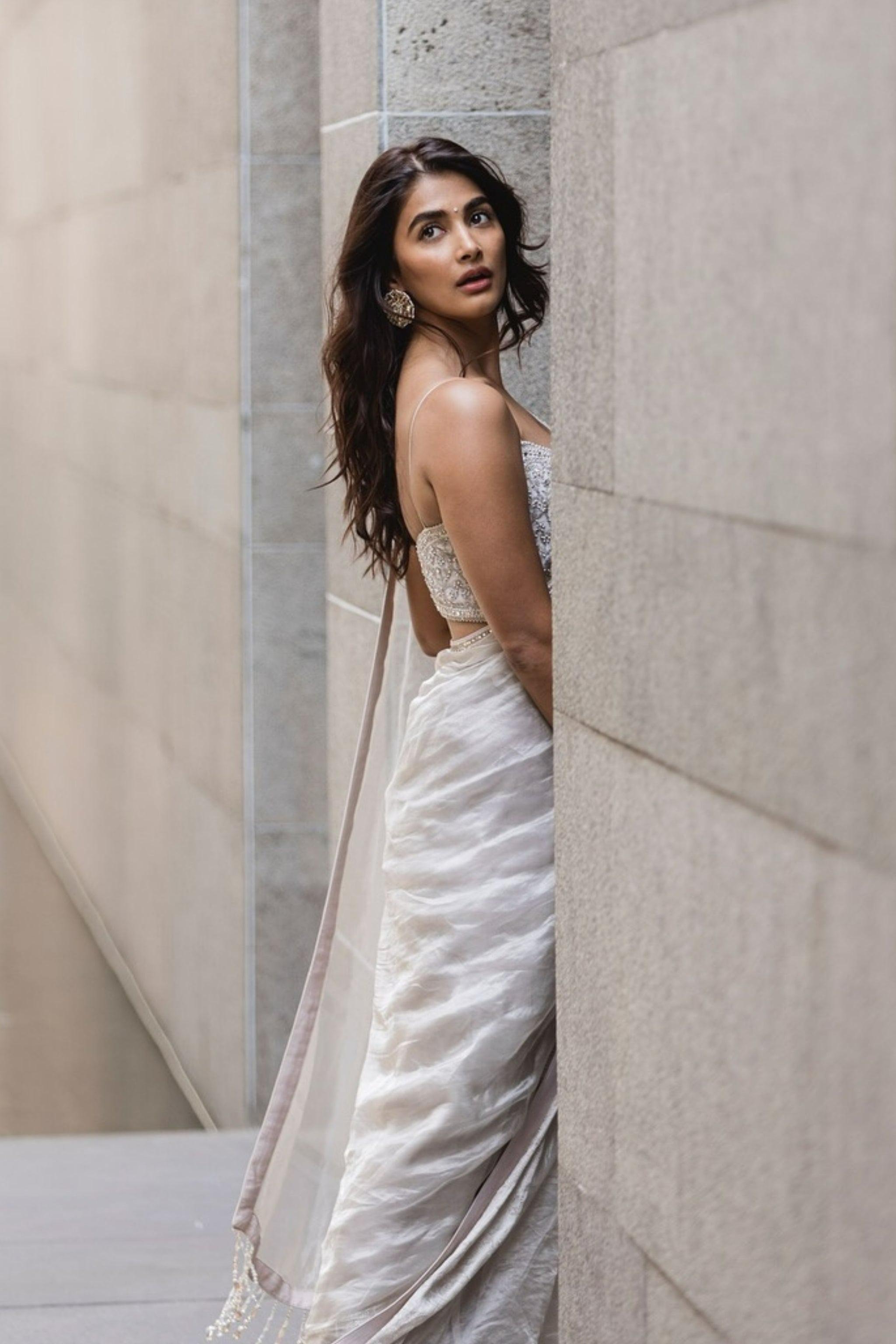 Pooja Hegde Standing Beside Stone Wall in Silver White Saree