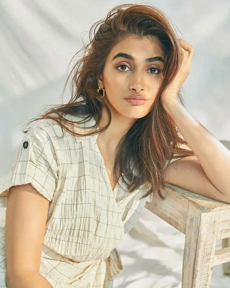 Pooja Hegde in a Light Dress Sitting Near a Chair Image