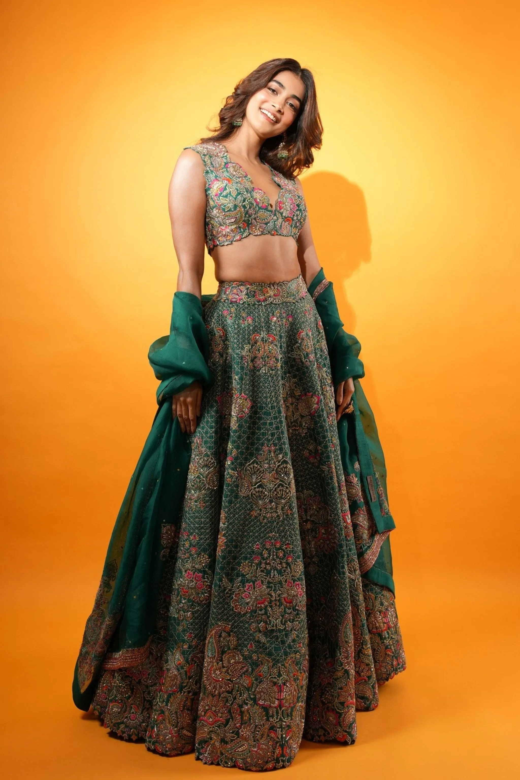 Pooja Hegde in Green Lehenga Smiling in Front of Orange Wall
