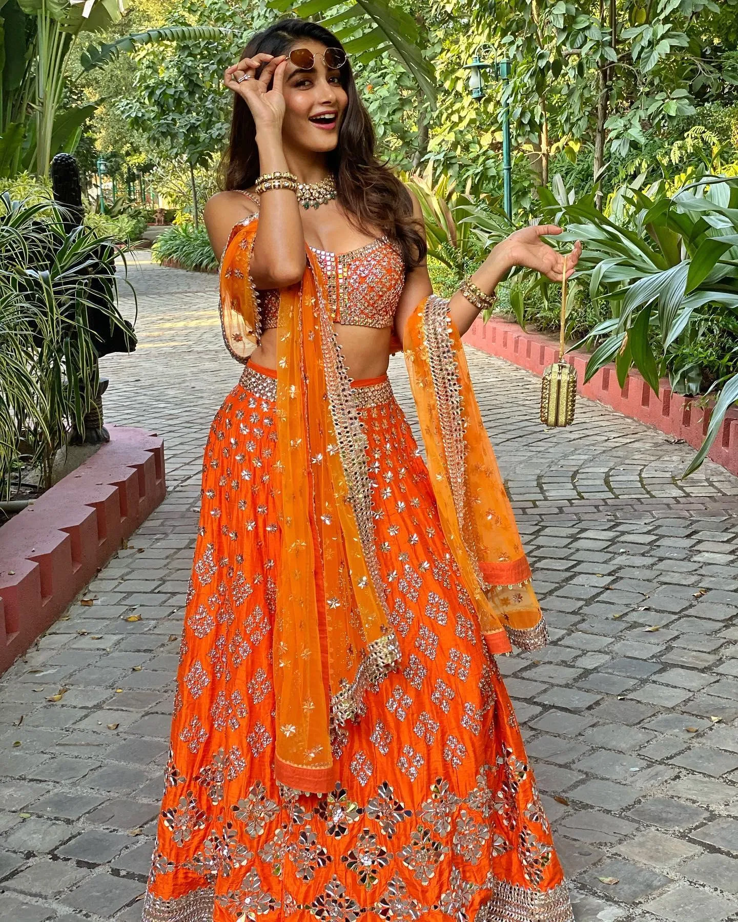 Pooja Hegde in Vibrant Orange Lehenga Walking Garden Path