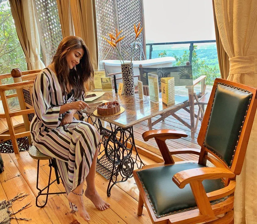 Pooja Hegde Reading in a Cozy Modern Restaurant Wallpaper