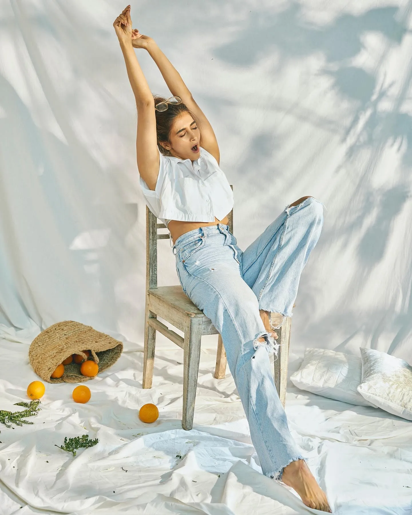 Pooja Hegde Relaxing on Chair Wearing White Top and Jeans