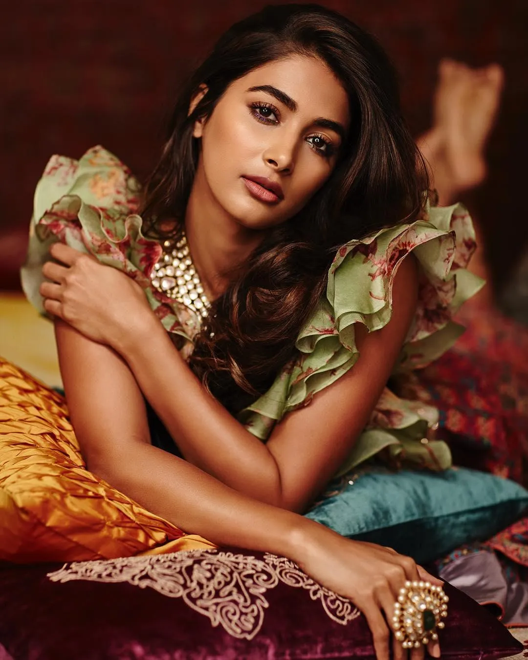 Pooja Hegde Resting on Colorful Pillows with Grace Image