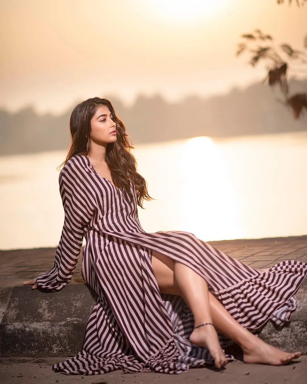 Pooja Hegde Sitting Calmly By Water in Striped Dress