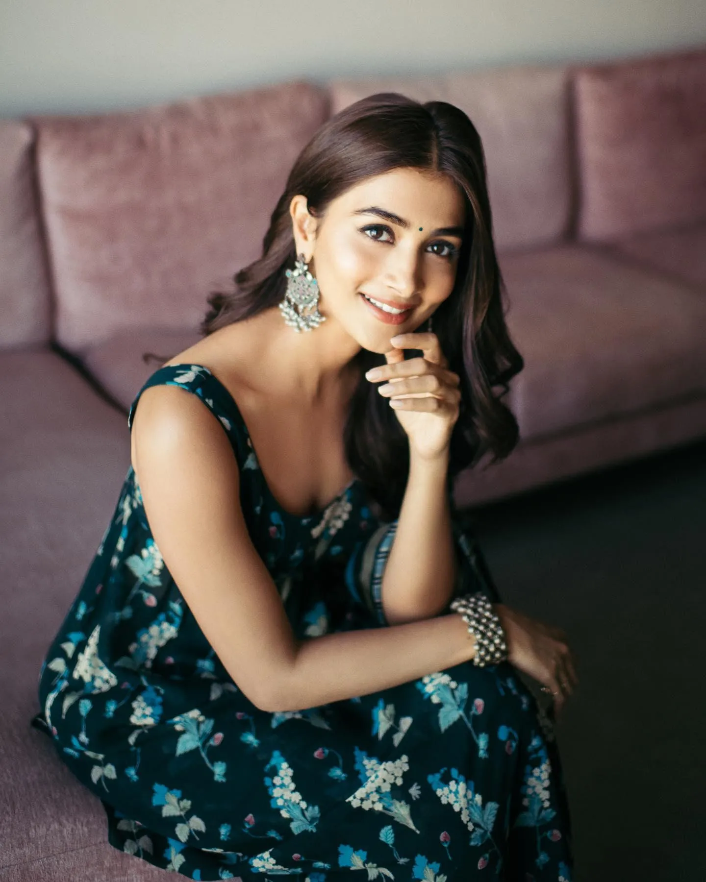 Pooja Hegde Sitting on Couch in Floral Dress with Soft Smile
