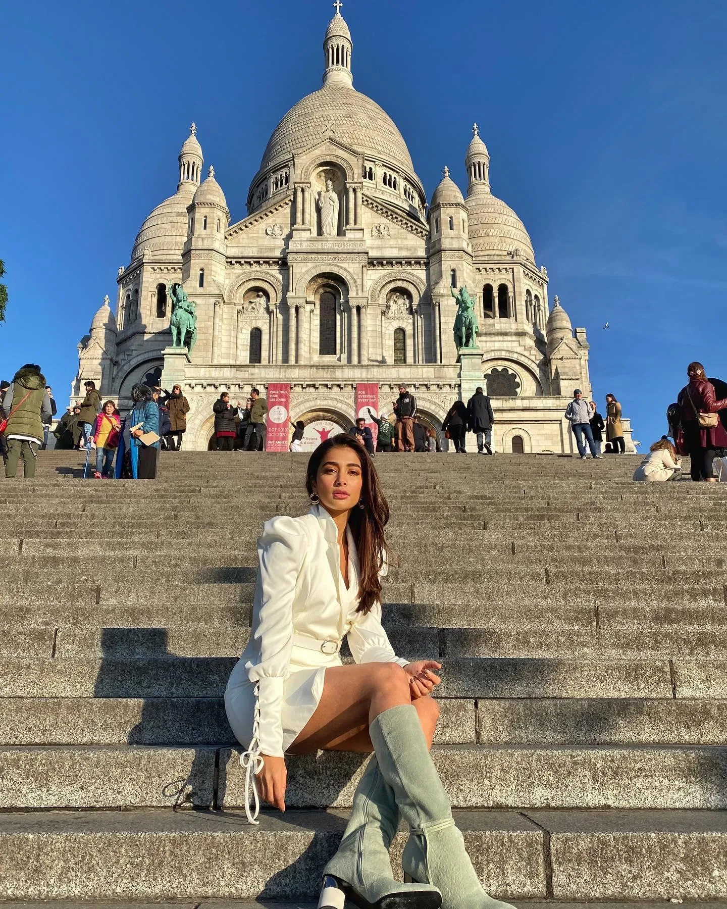 Pooja Hegde Sitting on Steps with European Monument Behind