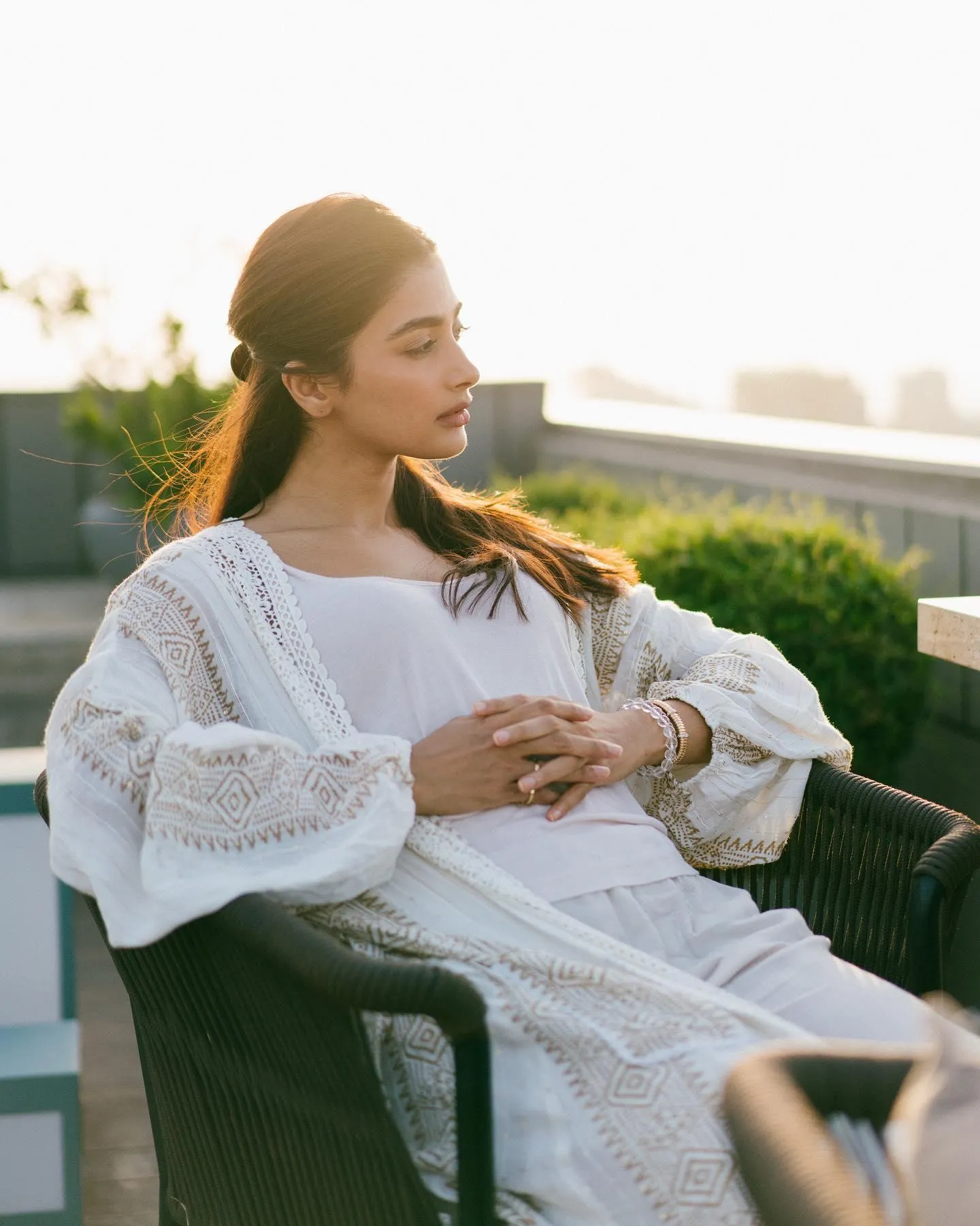 Pooja Hegde Sitting Outdoors in White Dress Looking Relaxed