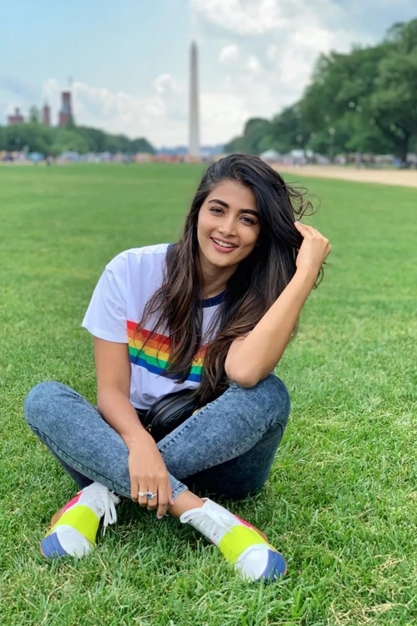 Pooja Hegde Smiling Sitting on Grass Wearing Casual Outfit