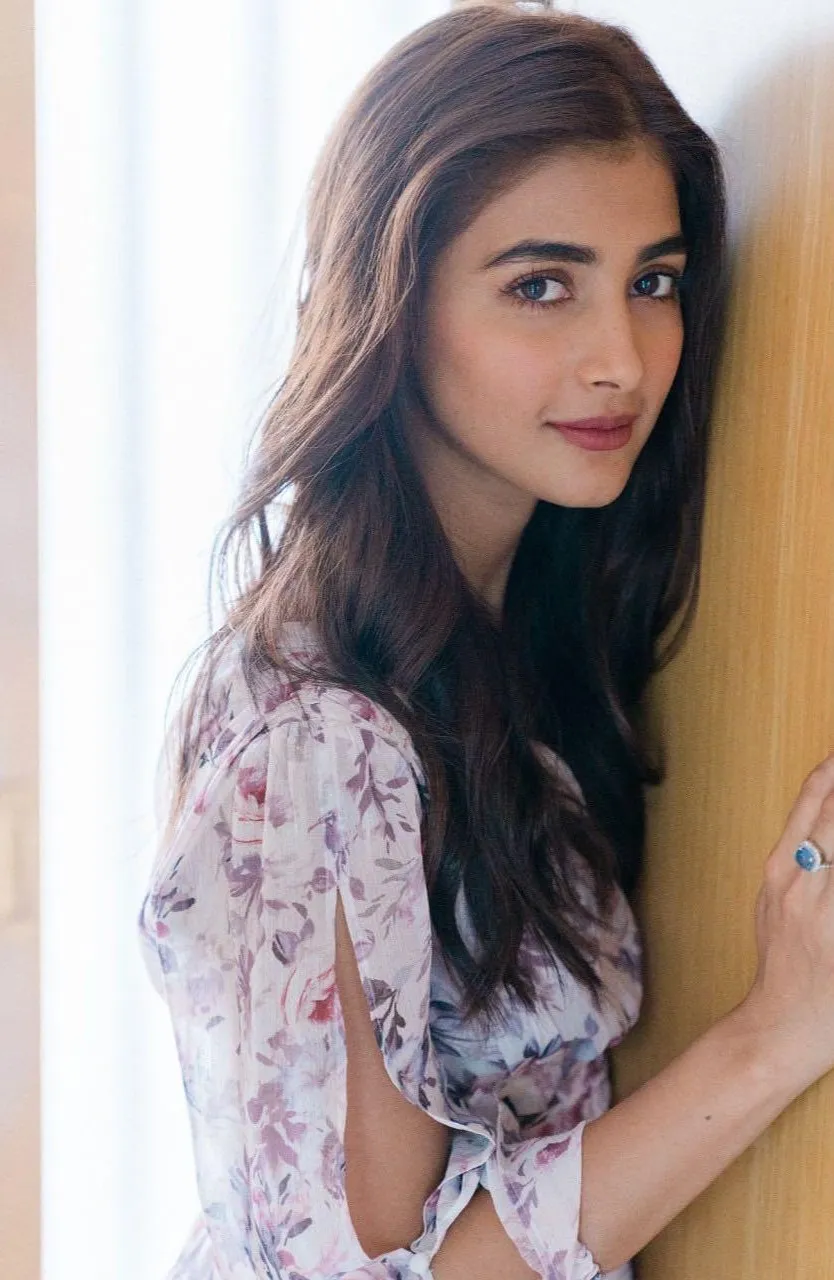 Pooja Hegde Smiling Softly in Floral Dress Near Wooden Wall