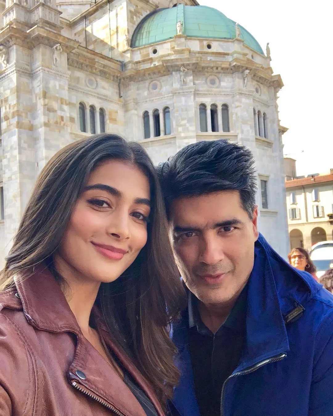 Pooja Hegde Smiling with Man Outdoors Near Historical Building