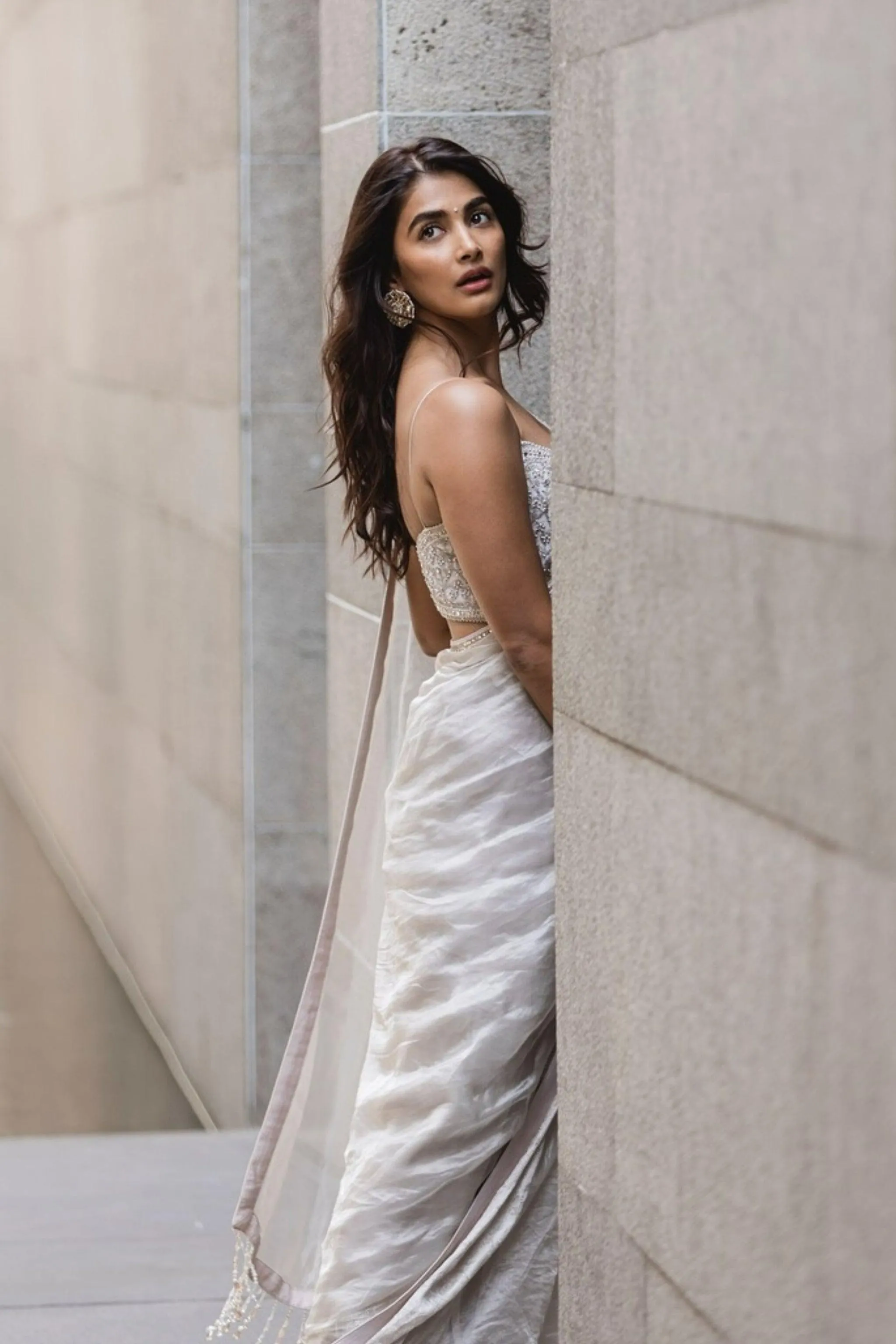 Pooja Hegde Standing Beside Stone Wall in Silver White Saree