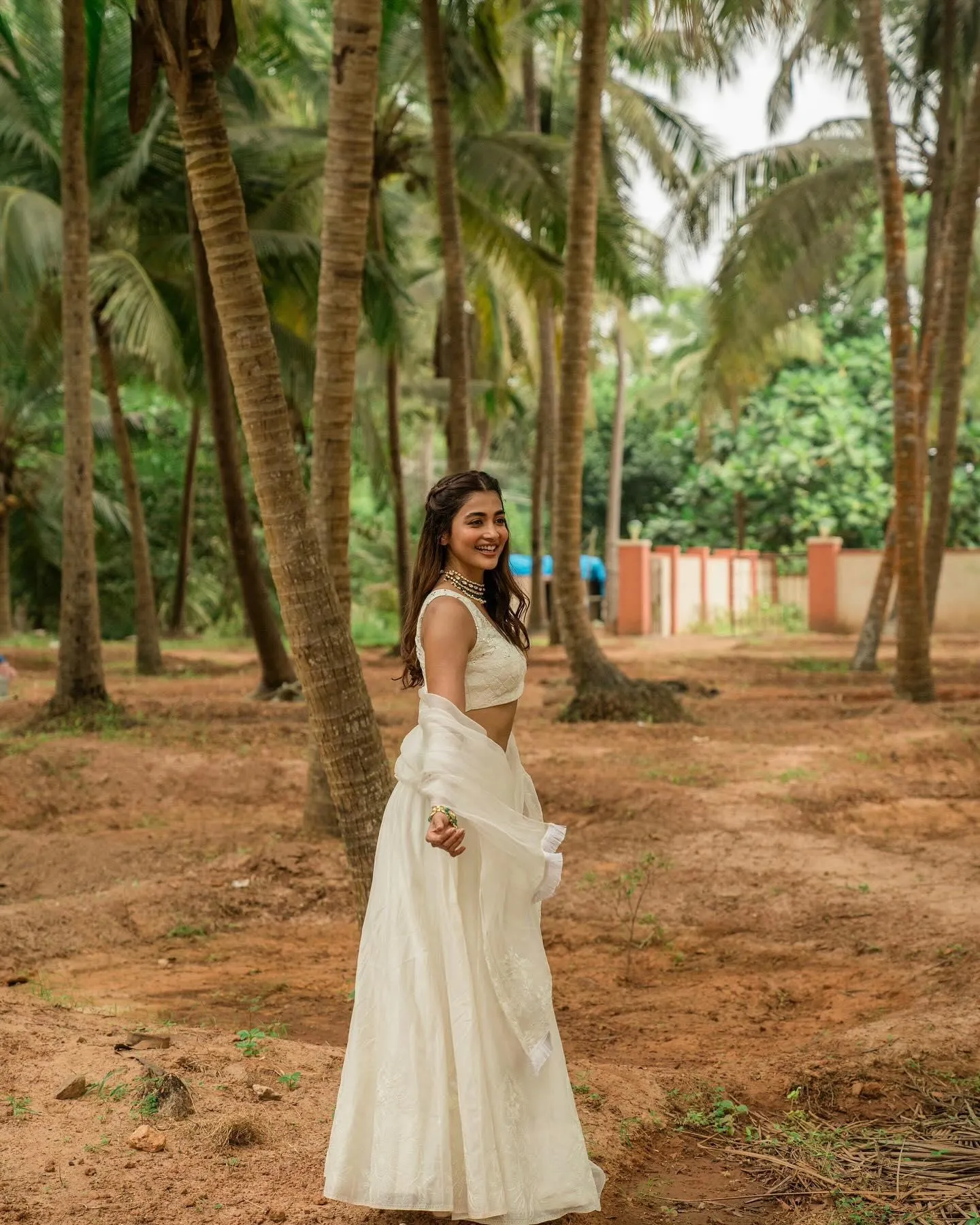 Pooja Hegde Walking in White Dress Under Tall Palm Trees