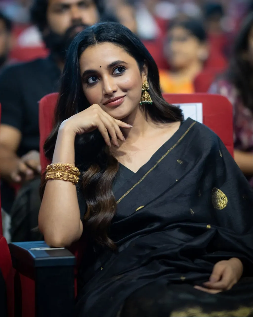 Actress Priyanka in black saree sitting at public event