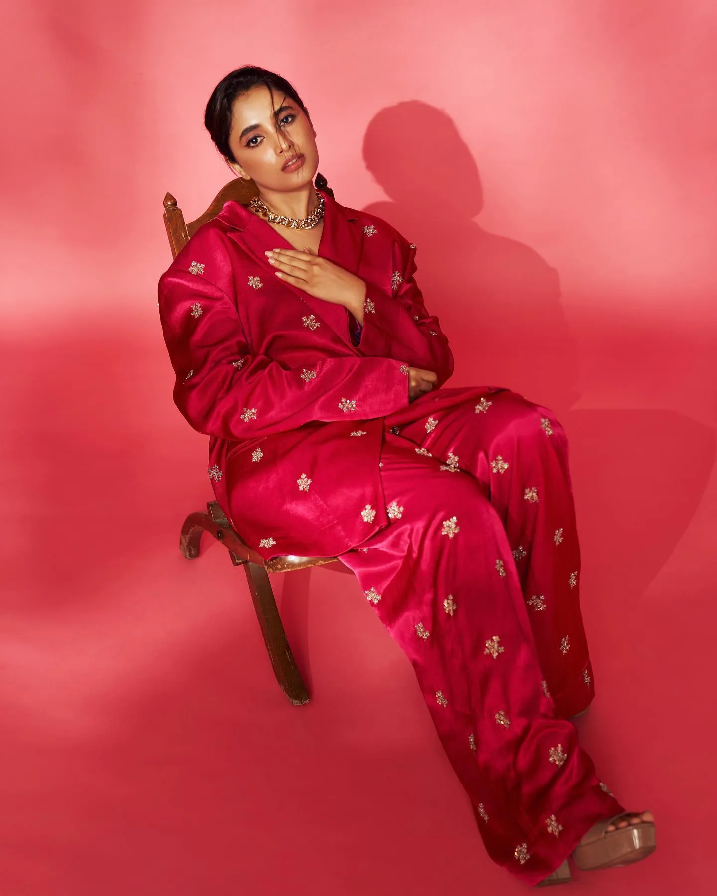 Actress Priyanka in red dress sitting against red backdrop