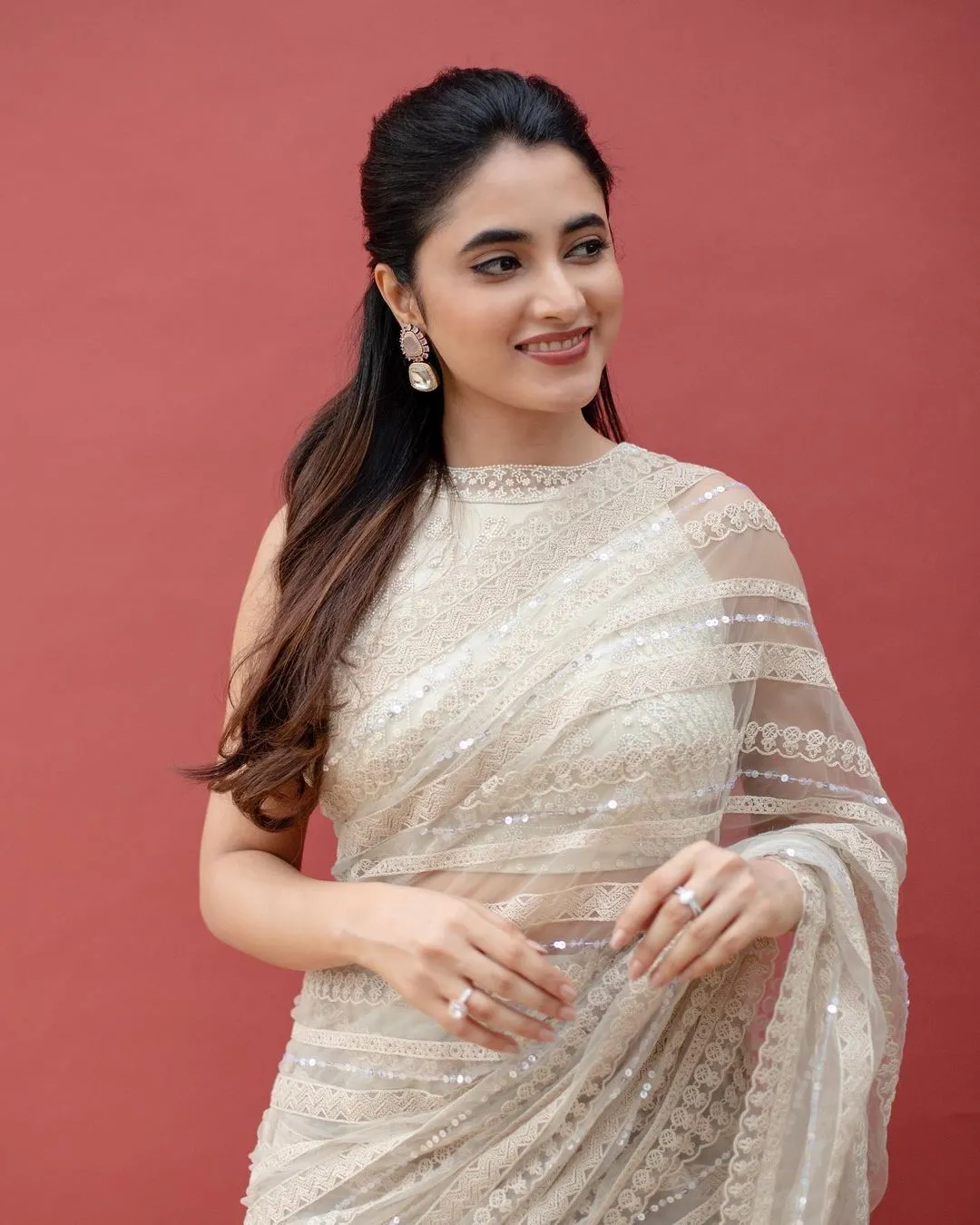 Elegant Priyanka Arul Mohan in Silver Saree on Red Backdrop