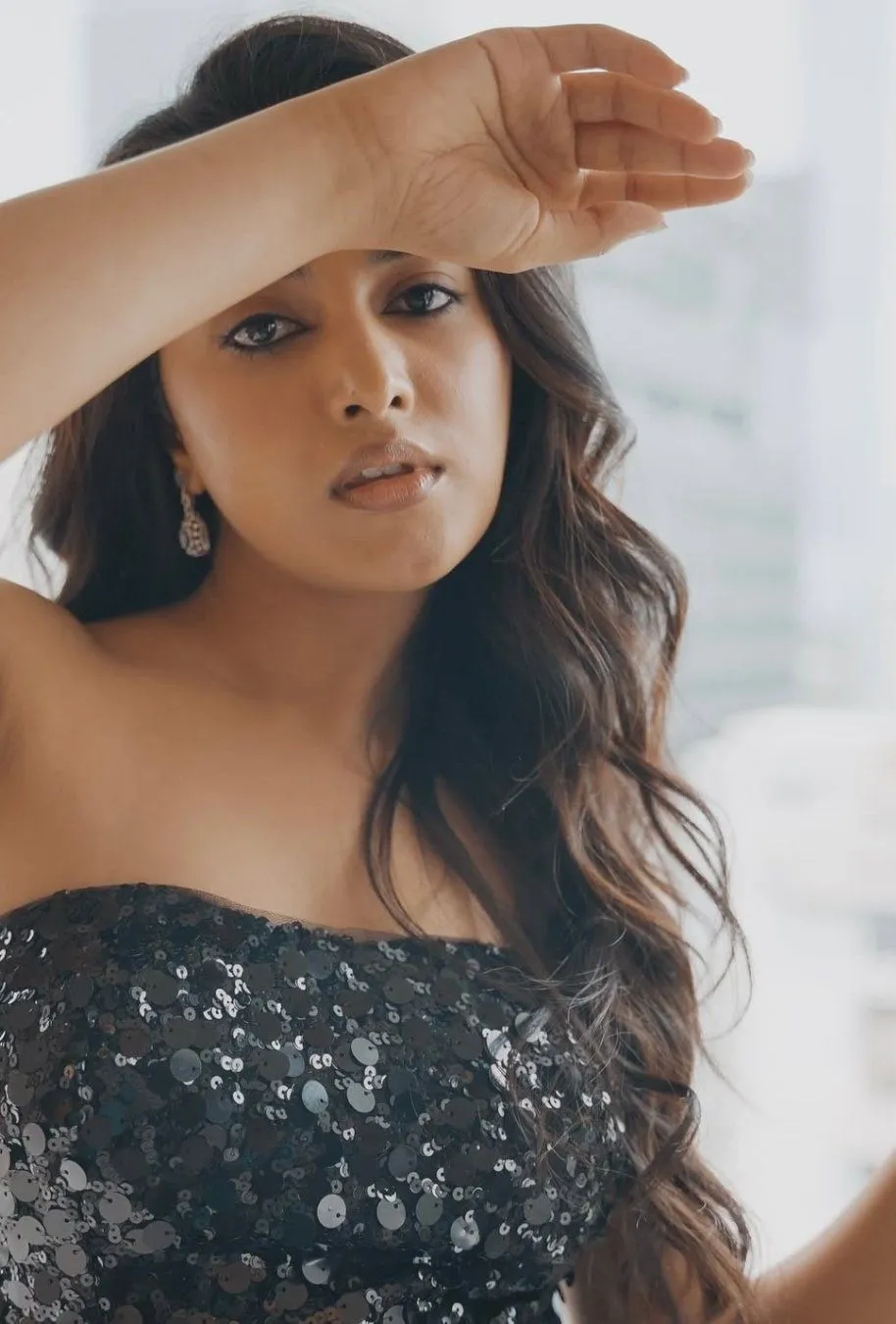 Glamorous Priyanka shielding eyes with arm in black dress
