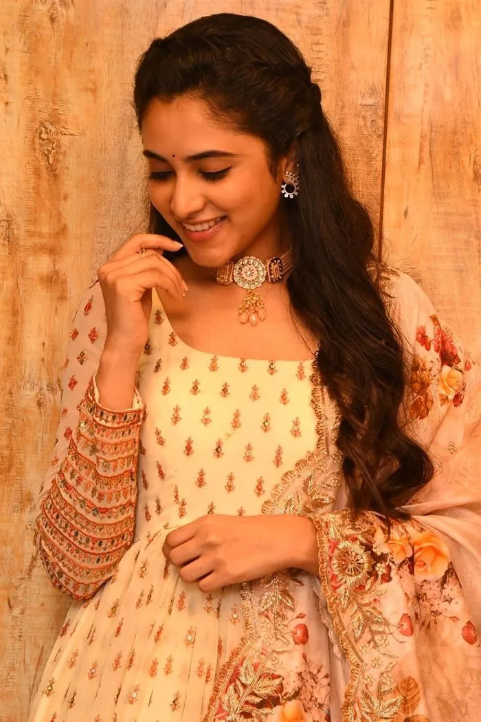 Priyanka Arul Mohan in orange outfit smiling against Wall