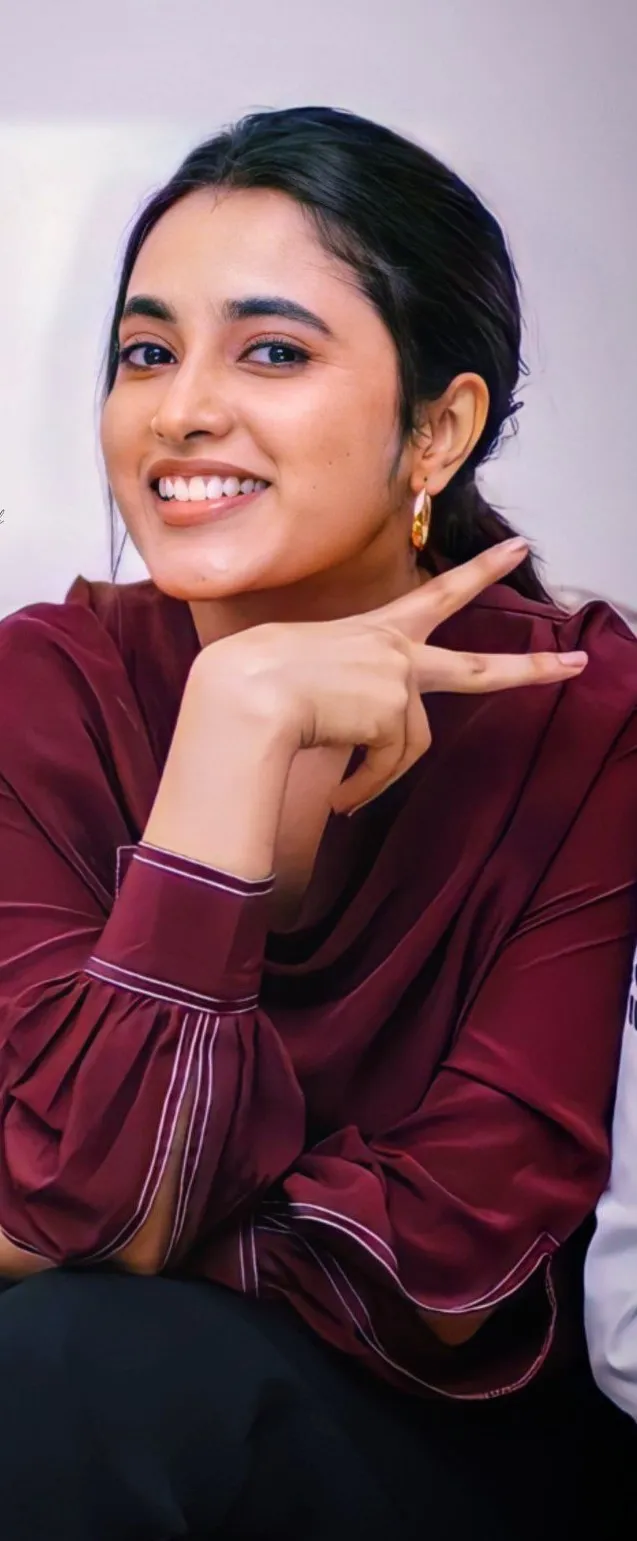 Priyanka Arul Mohan Smiling in a Maroon Satin Top Wallpaper